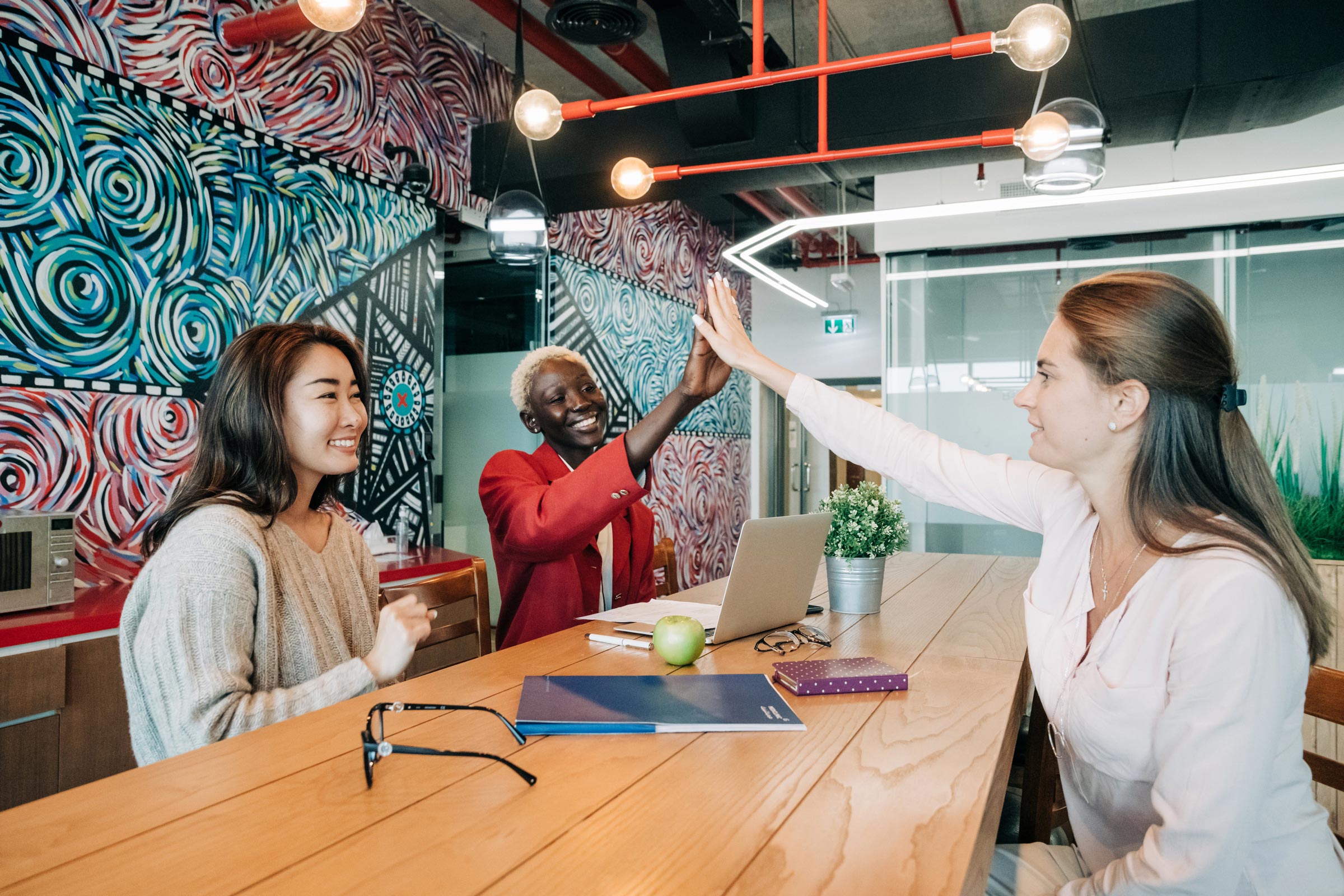 Team members high-fiving across long wooden table